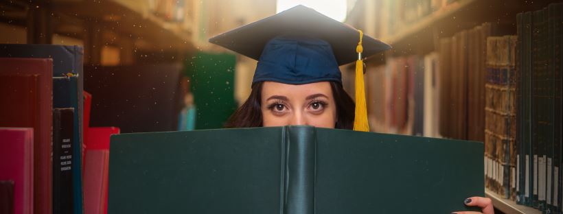 Graduate peering over a book